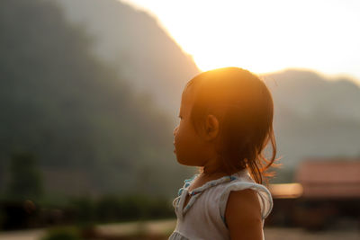 Portrait of woman standing against bright sun during sunset