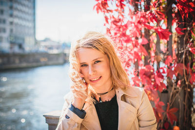 Portrait of young woman talking on phone by river