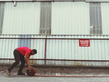 Side view of man walking on road against building