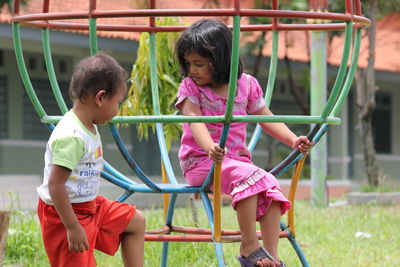 Siblings playing on jungle gym in playground