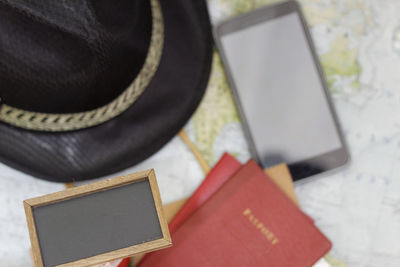 Directly above shot of passports and frames by phone and hat on map