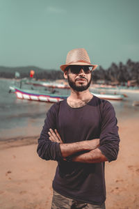 Portrait of young man standing at beach against sky