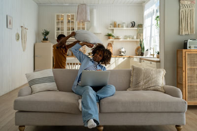 Young woman using laptop while sitting on sofa at home