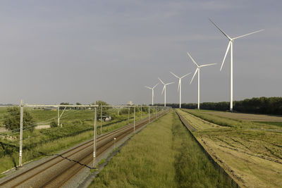 Wind turbines on field against sky