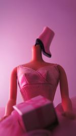 Close-up of mannequin and gift against pink background