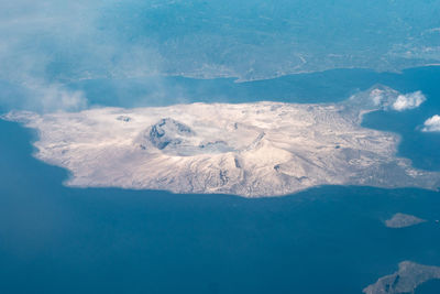 Aerial view of sea and mountain against blue sky