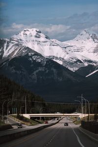 Road leading towards snowcapped mountains against sky