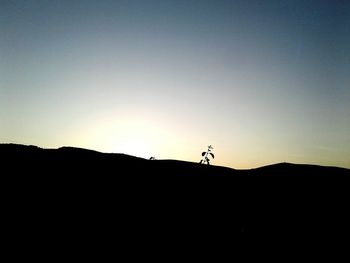 Silhouette man on desert against sky during sunset