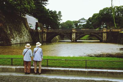 Rear view of people standing on bridge