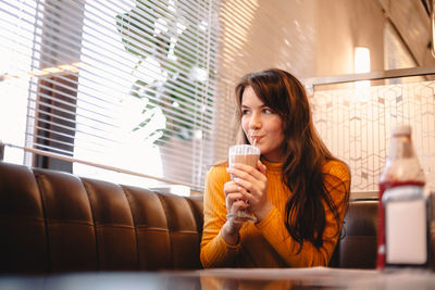 Teenage girl drinking chocolate milkshake in restaurant