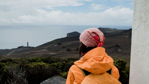 Woman looking at sea and mountain against sky