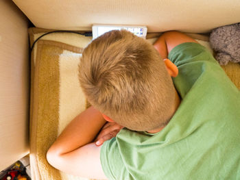 High angle view of boy using phone while lying on bed