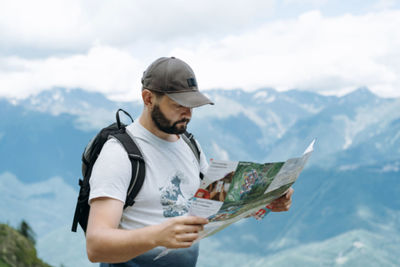 Tourist man hiking in mountains looking at the map for direction