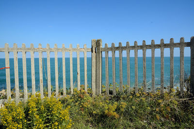 Wooden posts on beach against clear blue sky