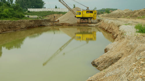 Construction site by lake against sky