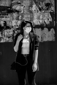 Portrait of young woman standing against wall