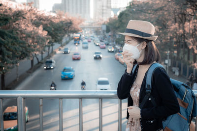 Young woman wearing mask standing on footbridge