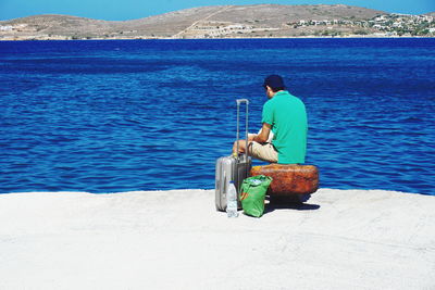 Rear view of man sitting at sea shore