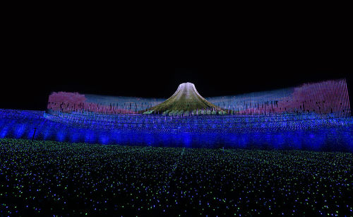 Illuminated buildings on field at night