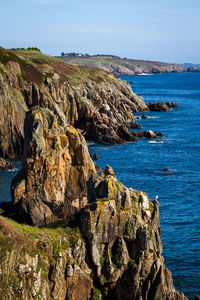 Scenic view of cliff by sea against clear sky