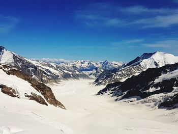 Scenic view of snowcapped mountains against blue sky