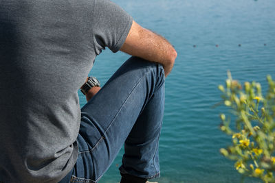 Rear view of man sitting by sea