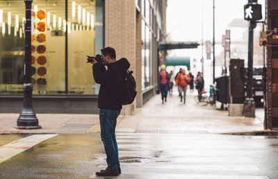 Full length of man photographing in city