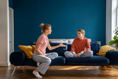 Upset mother arguing with child sitting on sofa. difficulties in raising teenage daughter