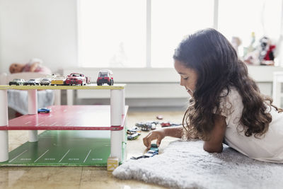 Side view of girl playing with toy car in day care center