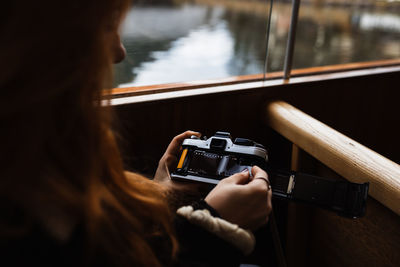 Rear view of woman photographing through mobile phone