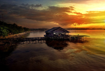 House by sea against sky during sunset