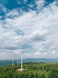 Wind turbines on field against sky