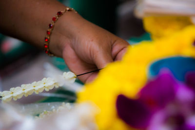 Cropped hand making garland at flower market