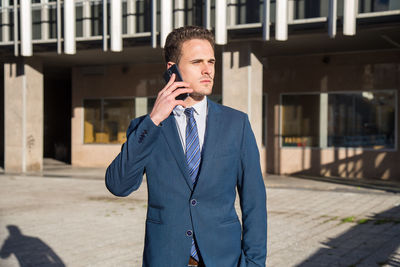 Businessman talking on phone while standing in city