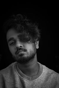 Close-up portrait of young man against black background