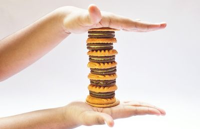 Close-up of hand holding cookies against white background