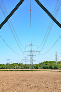 Electricity pylons on field against clear sky