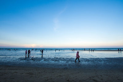 People at beach against blue sky