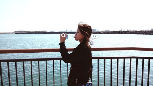 Woman standing by railing against sea