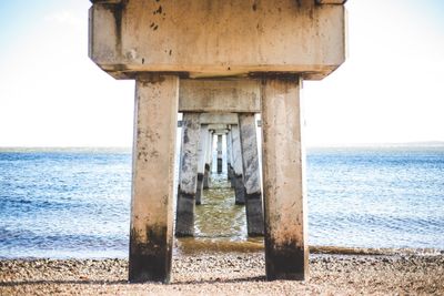 Wooden posts on beach against sky