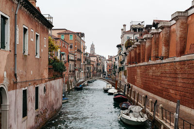 Gondolas moored on grand canal amidst buildings against sky