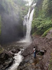 Rear view of man standing against waterfall