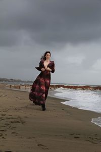 Girl running on beach against sky