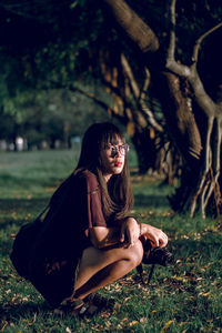 Young woman crouching on grass at park