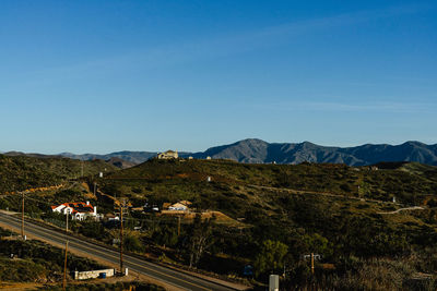 Road by mountains against clear blue sky