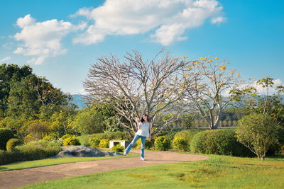 Rear view of woman walking on field against sky