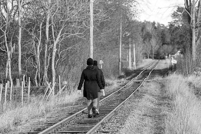 Rear view of friends walking on railroad track