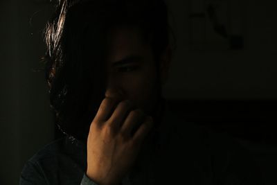 Close-up of thoughtful young man standing in darkroom