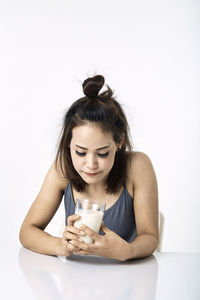 Young woman drinking coffee cup against white background