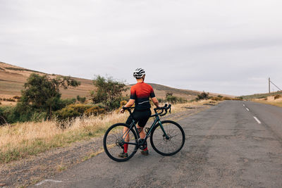 Man riding bicycle on road against sky